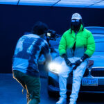 Man sitting on car for music video