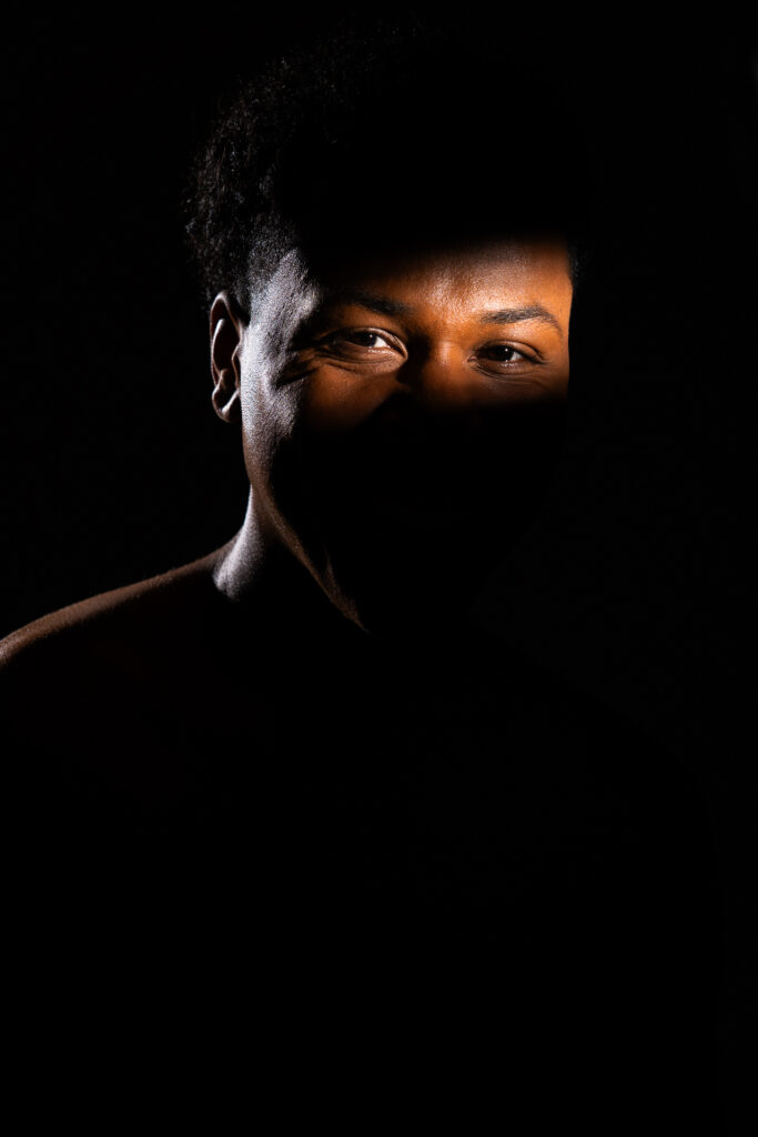 Man in darkness with strip of light across eyes