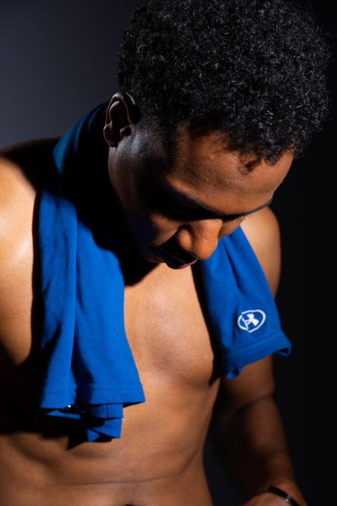 Shirtless man looking down with tank top around his neck