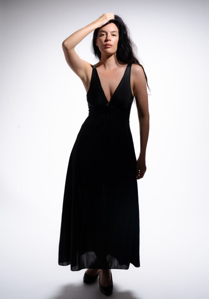 Woman in black dress holding back hair with her right hand